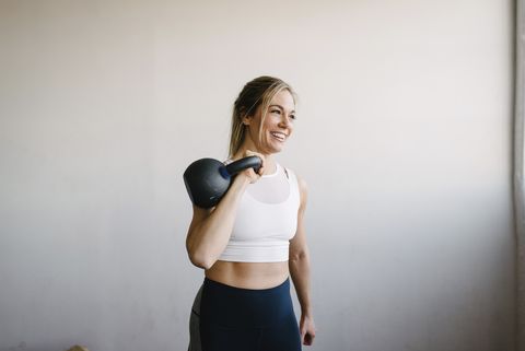 smiling-female-athlete-carrying-kettlebell-while-royalty-free-image-1651048779.jpg